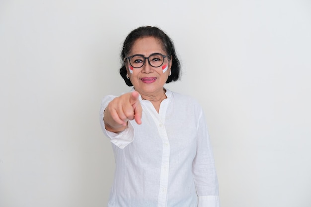 Elderly woman wearing Indonesia flag sticker in her cheeks pointing to the camera