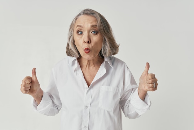 Elderly woman in white shirt emotions light background