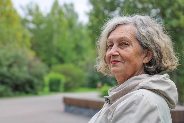 An elderly woman with gray hair is warmly dressed in cool weather Retirement age