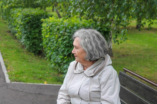 An elderly woman with gray hair is warmly dressed in cool weather Retirement age