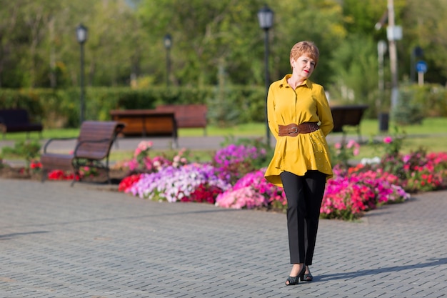 An elderly woman with short dyed hair standing in a city park