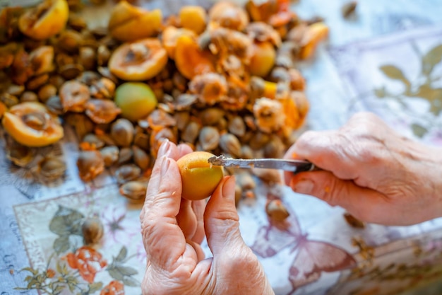 Elderly women's hands cut apricots for jam. Preparation of apricot blanks