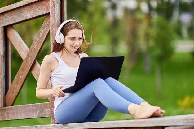 Elearning or online education laptop on lap of young woman in public park