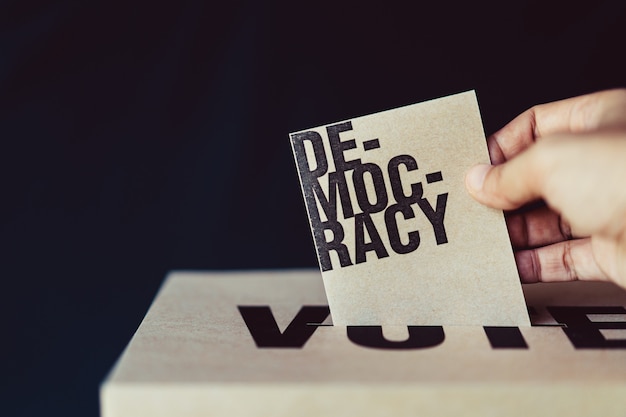 Election card insert in vote box, democracy concept, retro tone