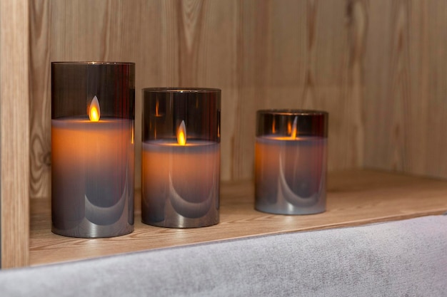 Electric candles on a wooden shelf in the interior Closeup Cozy and comfortable atmosphere in the design of the room