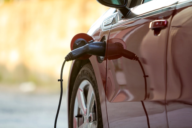 Electric car being recharged on bright sunny street.