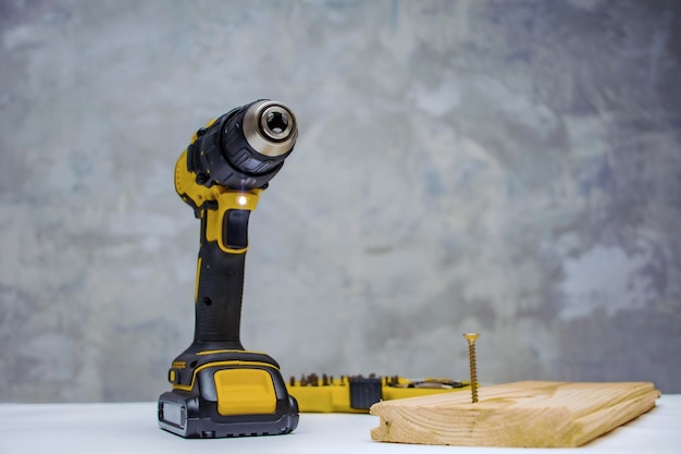 Electric cordless screwdriver on the battery on the table with a selftapping screw in the board