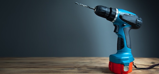 Electric drill on a wooden table with dark background