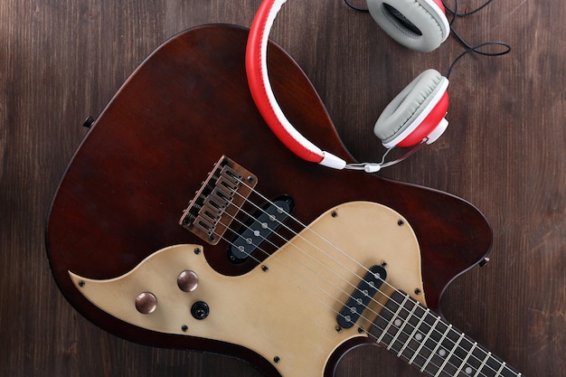 Electric guitar with headphones on wooden table close up