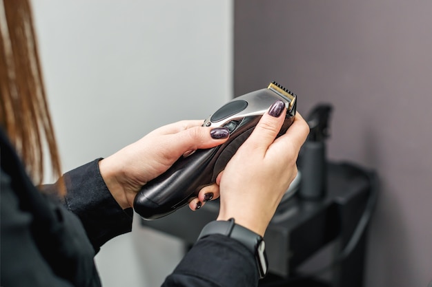 Electric hair trimmer in hands of female hairdresser