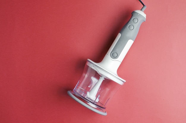 Electric hand blender with a jar on red background. Top view, Flat lay