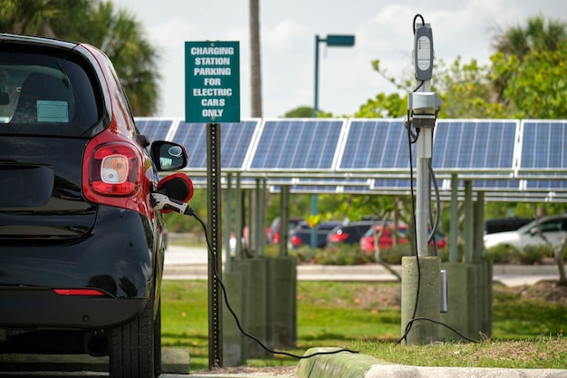 Electric plugin car charging with electricity from solar renewable power source parked on city street