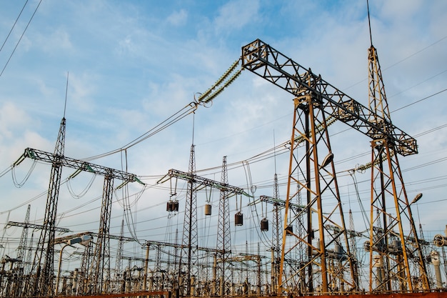 Electric pylons and high-voltage power lines against the backdrop of a bare sky with white clouds.