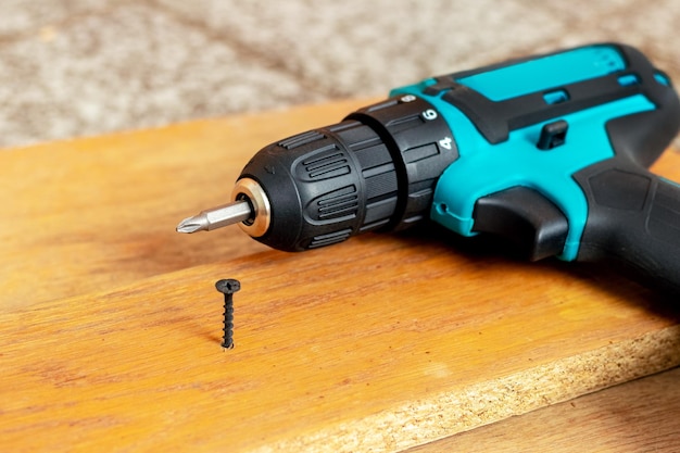 Electric screwdriver near the screw screwed into the chipboard