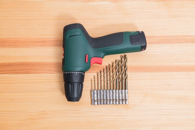 An electric screwdriver with drills lies on a wooden table