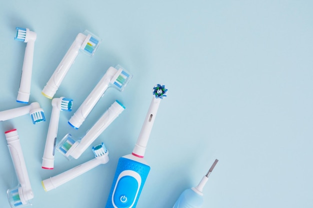 Electric toothbrush and multicolored replaceable nozzles on blue background