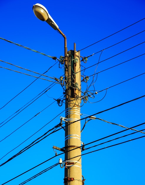 Electric wire and lamp on electrical pole with blue sky