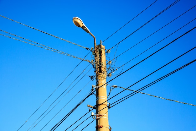 Electric wire and lamp on electrical pole with blue sky