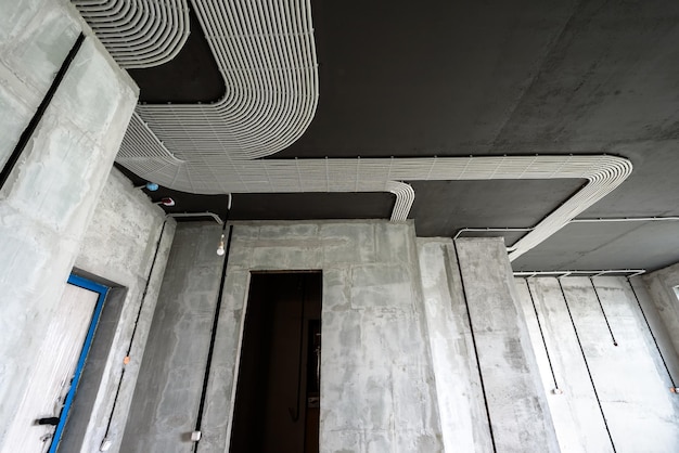 Electrical cables and pipes on house concrete ceiling and walls