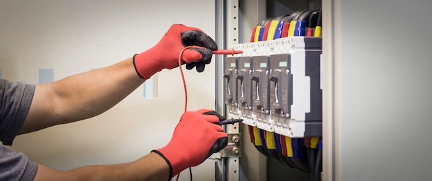 Electrical engineer checking the operation of electrical control cabinet, maintenance concept.