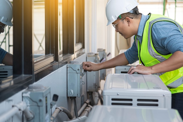 Electrical engineer is checking and maintenance air conditioner system.