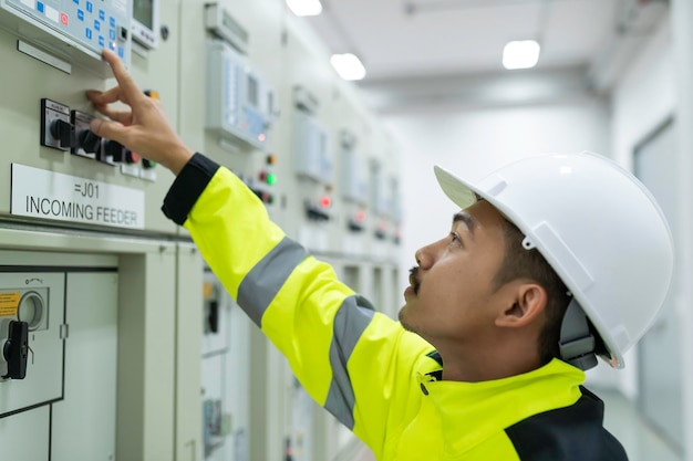 Electrical engineer man checking voltage at the Power Distribution Cabinet in the control roompreventive maintenance YearlyThailand Electrician working at company