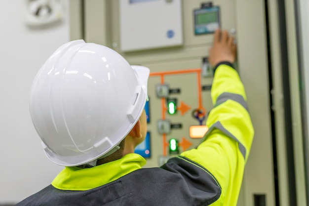 Electrical engineer man checking voltage at the Power Distribution Cabinet in the control roompreventive maintenance YearlyThailand Electrician working at company