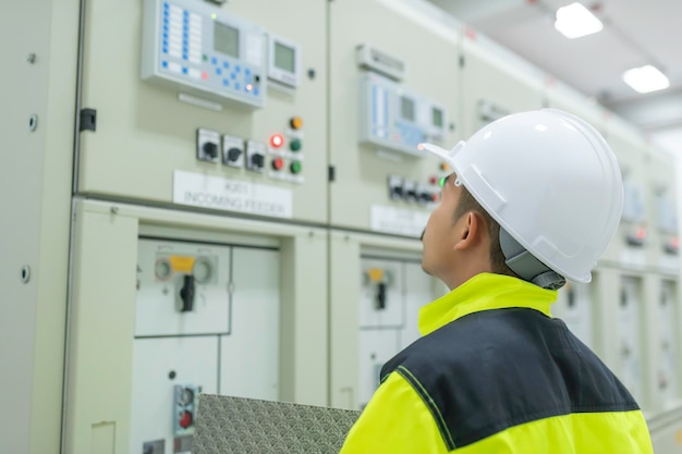 Electrical engineer man checking voltage at the Power Distribution Cabinet in the control roompreventive maintenance YearlyThailand Electrician working at company