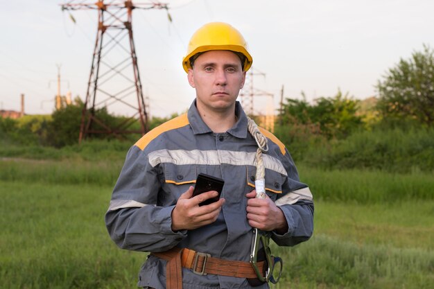 electrical engineer in protective clothing with a mobile phone in his hands