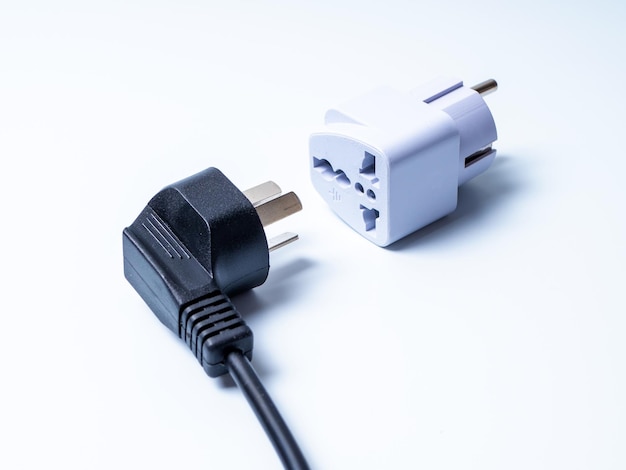 An electrical plug lying next to an adapter for another type of electrical plug