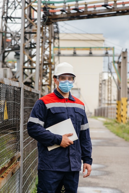 An electrical substation engineer inspects modern high-voltage equipment in a mask at the time of pandemia. Energy. Industry.