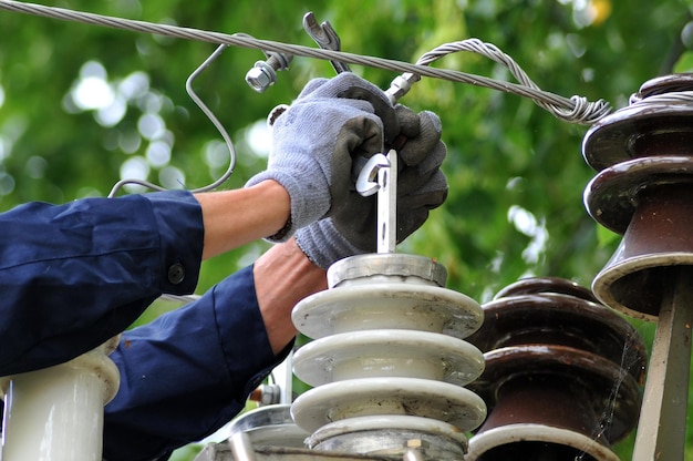 An electrician changes a damaged insulator