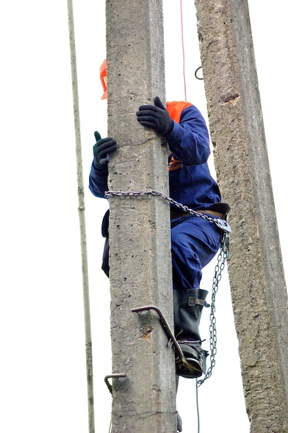 An electrician climbs a concrete pole