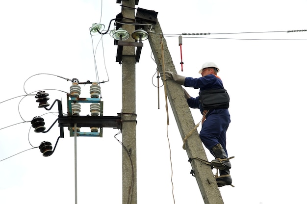 An electrician climbs a pole of a power line in order to eliminate a line break.