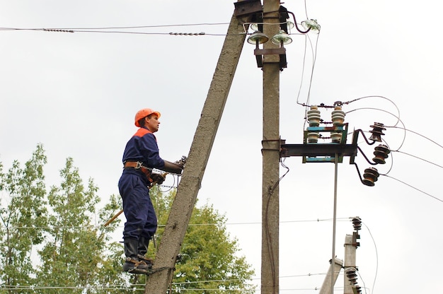 An electrician climbs a pole of a power line in order to install a ground to eliminate a line break