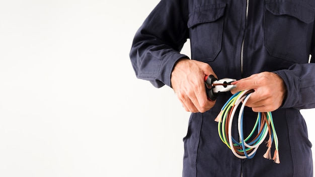 Electrician cutting wire through the plier against white background