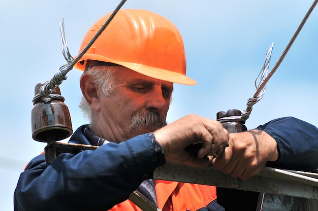 Electrician on an electric pole changes a damaged insulator