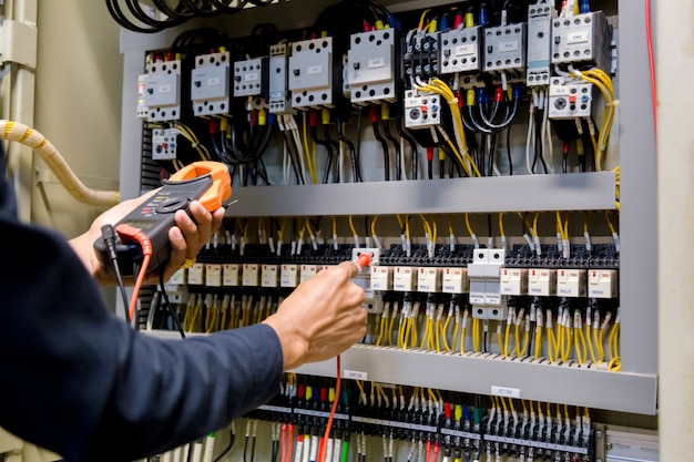 Electrician engineer work  tester measuring  voltage and current of power electric line in electical cabinet control.