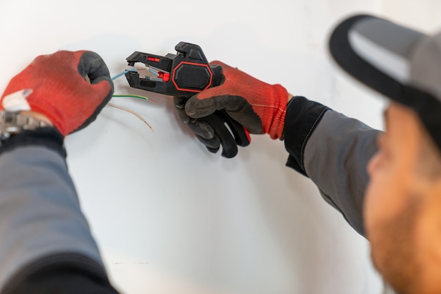 electrician exposes edges of wires with a special tool
