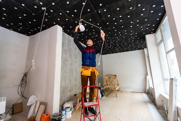 Electrician installer with a tool in his hands, working with cable on the construction site. Repair and handyman concept. House and house reconstruction.