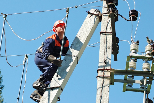 An electrician installs the grounding on the power line before repairing it.