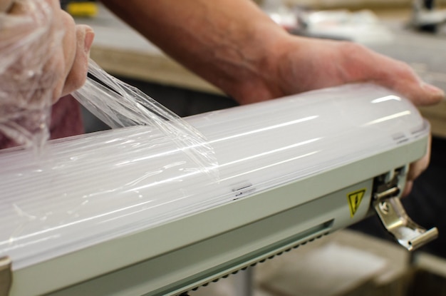 Photo electrician installs new ceiling fluorescent lamps. repair and service concept. removing the protective film.