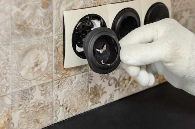 An electrician is installing switches and sockets on the wall close up