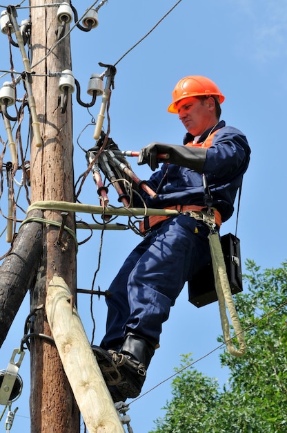 Electrician lineman repairman worker  installs the grounding on the power line before repairing it.