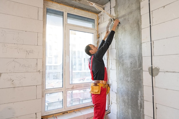 Electrician measuring voltage of air conditioner in construction site.