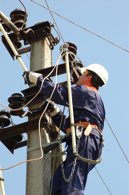 Photo an electrician on a pole carries out the grounding of an overhead power line