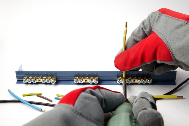 Electrician in protective gloves fixes electric cables with a screwdriver