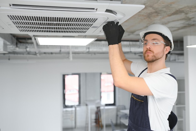 Electrician repairing air conditioner indoors