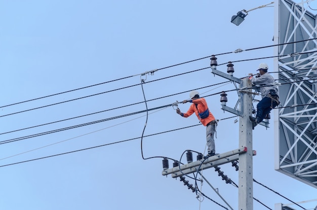 Electricians are climbing on electric poles to install and repair power lines.