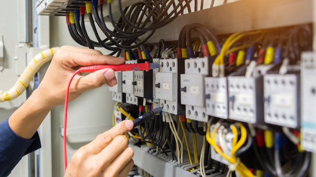 Electricians hands testing current  electric in control panel.